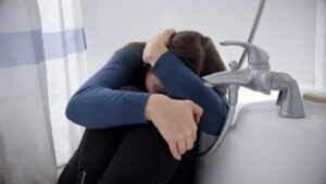 woman in bathtub covering face