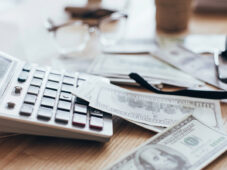 calculator, money, and glasses on cluttered desk