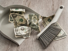 dustpan and brush sweeping up dollar bills