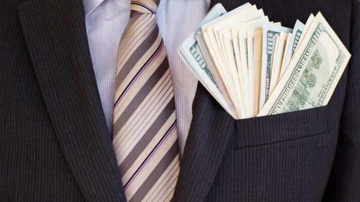 close up of man in suit with money in his suit jacket pocket